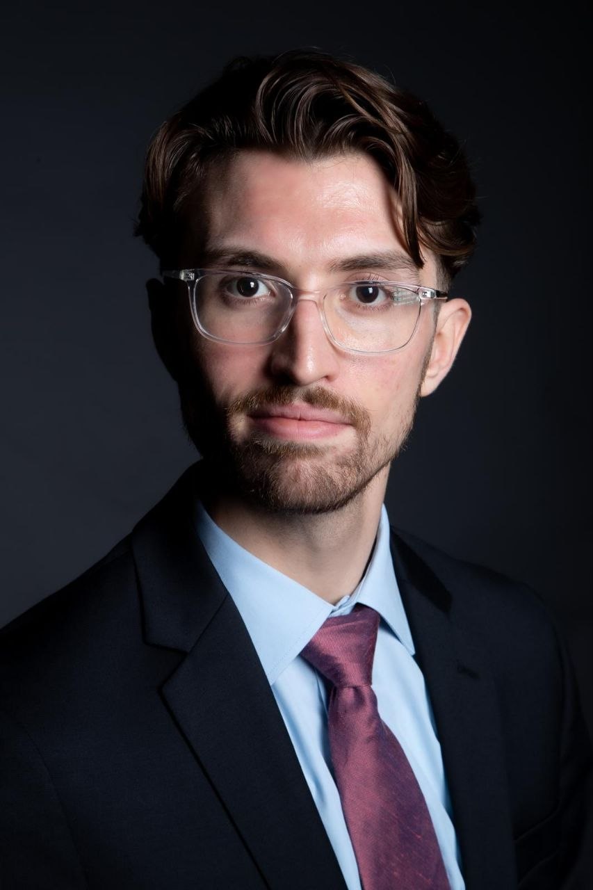 Portrait of a man with glasses wearing a gray shirt.